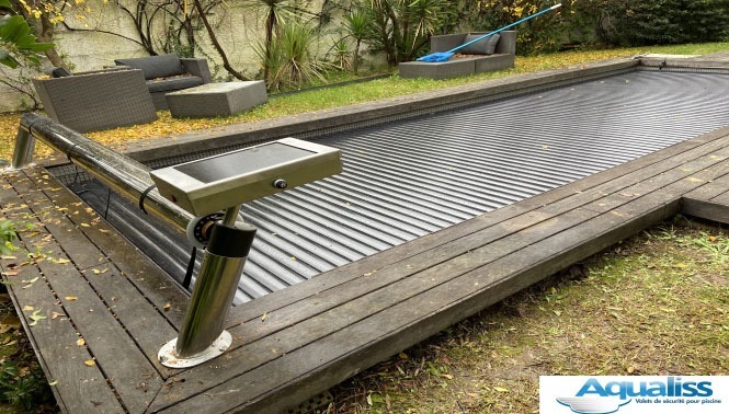 Volet hors sol pour piscine avec boîtier solaire et lames en polycarbonate, fermé sur la piscine, photographié en journée.