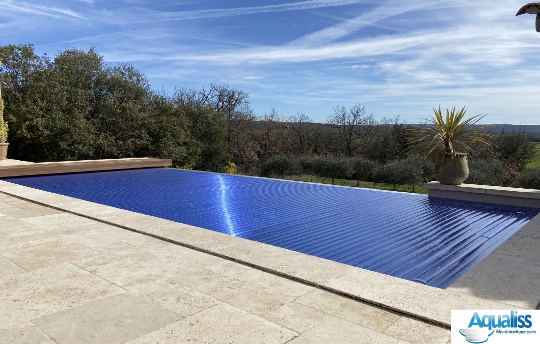 Volet de piscine avec lames en polycarbonate, en position fermée, installé en extérieur sous la lumière du jour.