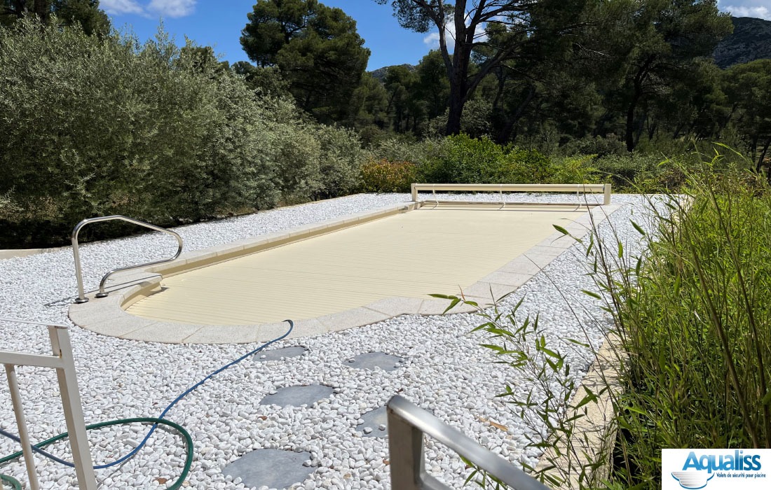 Volet de piscine hors sol couleur vanille, fermé sur la piscine, photographié en pleine journée.